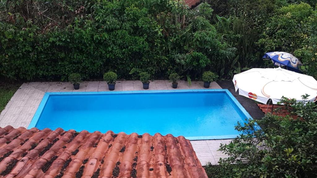 a swimming pool and an umbrella next to a house at Pousadinha Ateliê da Maite in Paraty