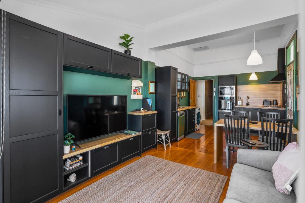a living room with a large television and a kitchen at Rawsons shack Beachfront unit suits single or couple in Henley Beach South