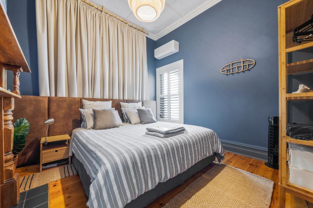 a blue bedroom with a bed and a window at Rawsons shack Beachfront unit suits single or couple in Henley Beach South