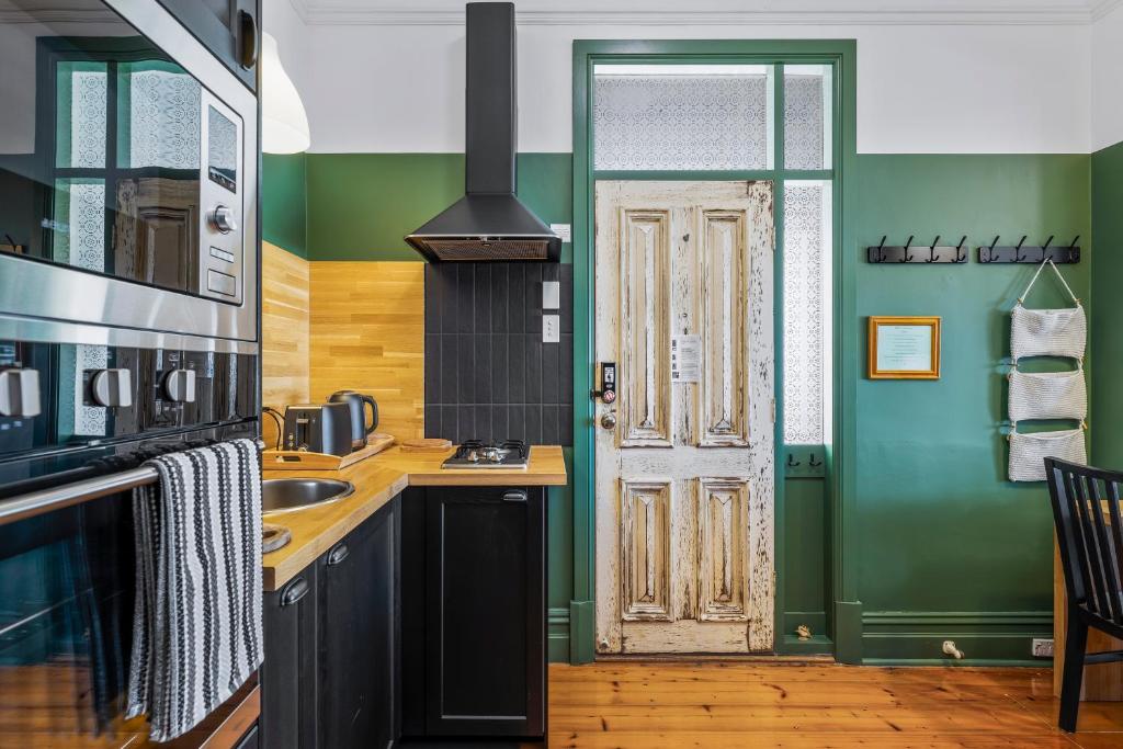 a kitchen with green and black walls and a door at Rawsons shack Beachfront unit suits single or couple in Henley Beach South