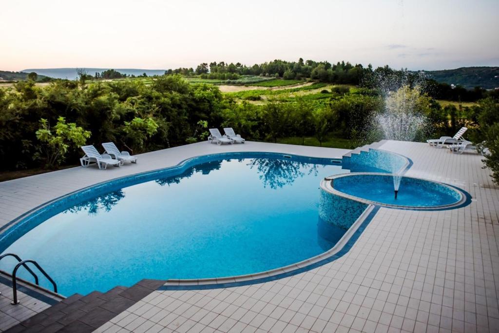 uma grande piscina com uma fonte e cadeiras em Villa Monako 2000 em Medjugorje