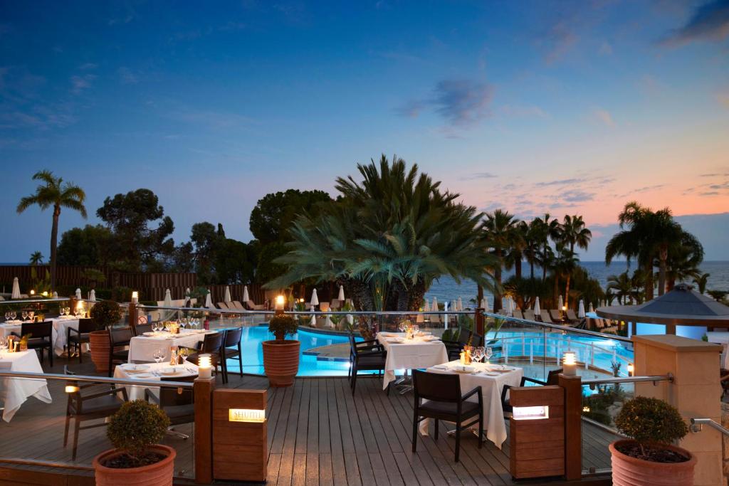 a restaurant with tables and chairs and a pool at Mediterranean Beach Hotel in Limassol