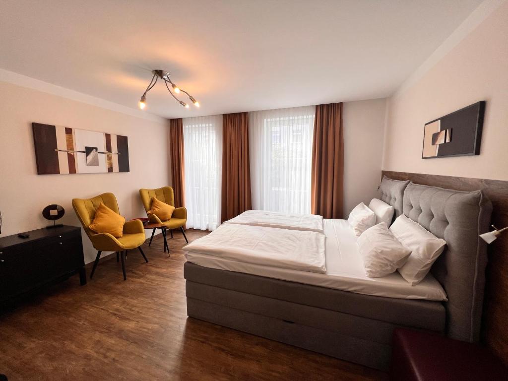 a bedroom with a large bed and two chairs at Hotel PrimaVera parco in Fürth