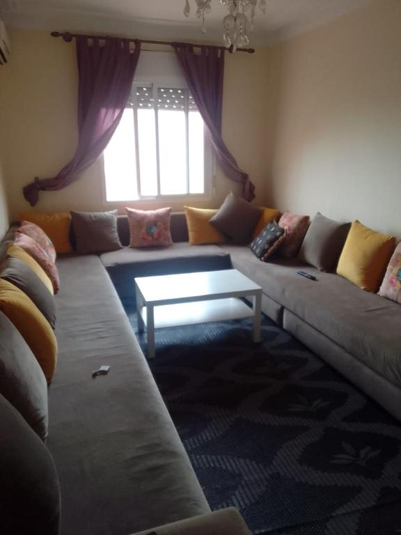 een woonkamer met een grote bank en een tafel bij Appartement à Tamansourt in Marrakesh