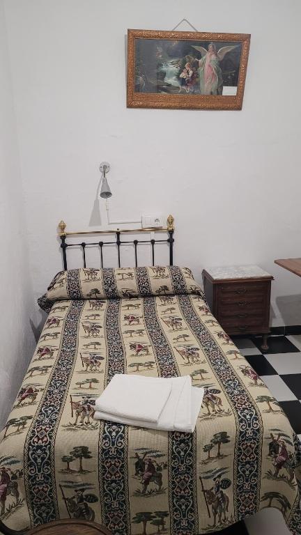 a bed with a quilt on it in a bedroom at Pensión San Benito Abad in Seville