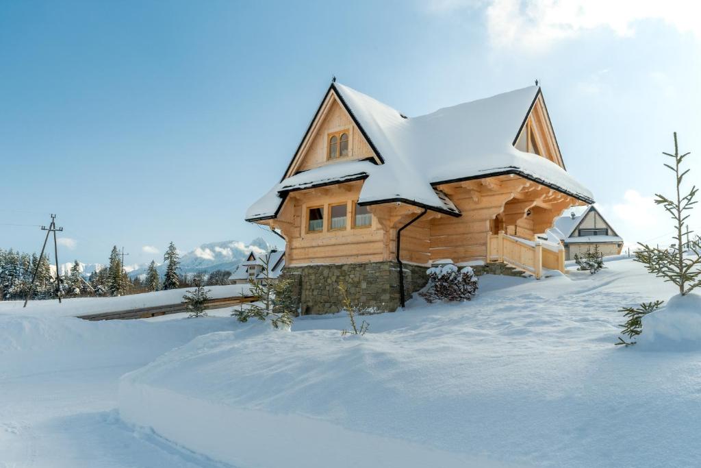 a log cabin with snow on the roof at Osada Roztoki - Luxury Chalets in Kościelisko