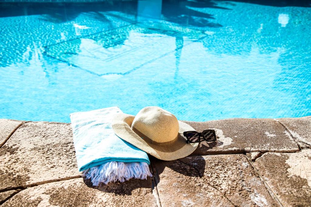 アルムニェーカルにあるHotel Victoria Playaのスイミングプールの横に座るわら帽子