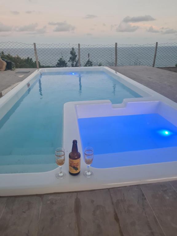 a swimming pool with two glasses and a bottle of wine at Village as casinhas in Uruçuca