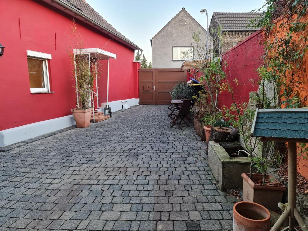 a courtyard with a red building and some plants at Schönste Lage am Rhein, behagliches Haus mit Kamin. in Cologne