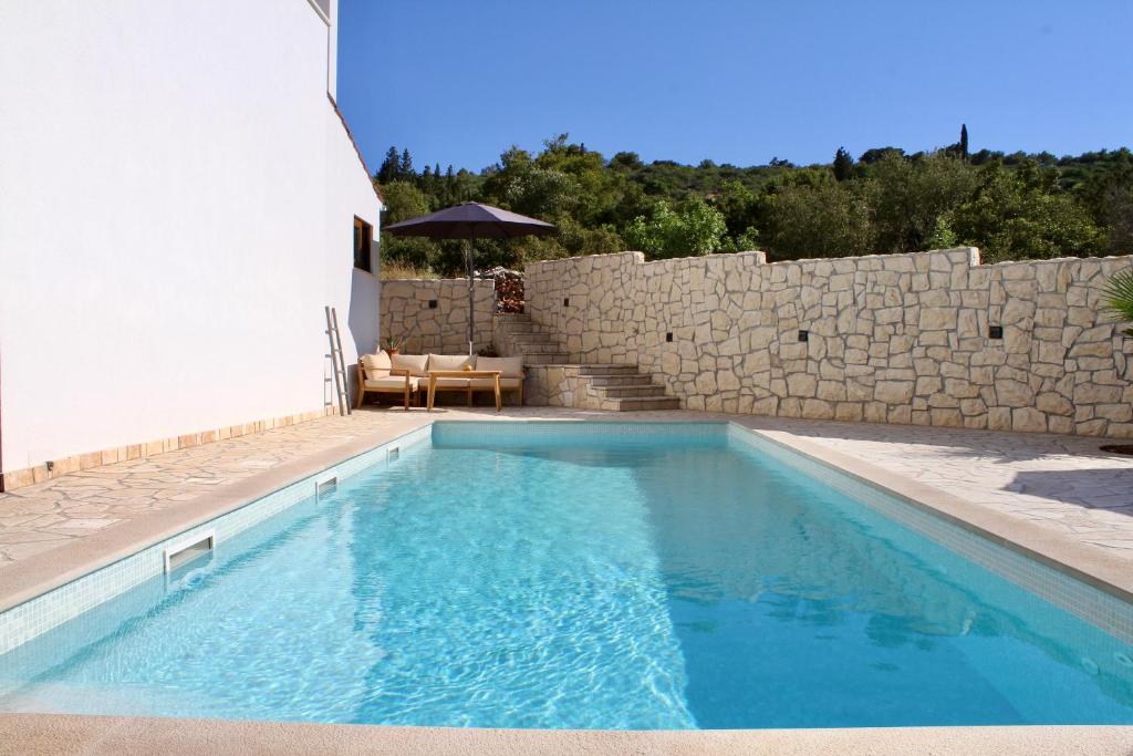 a swimming pool in front of a stone wall at Villa Bora - Ferienhaus am Meer in Slatine