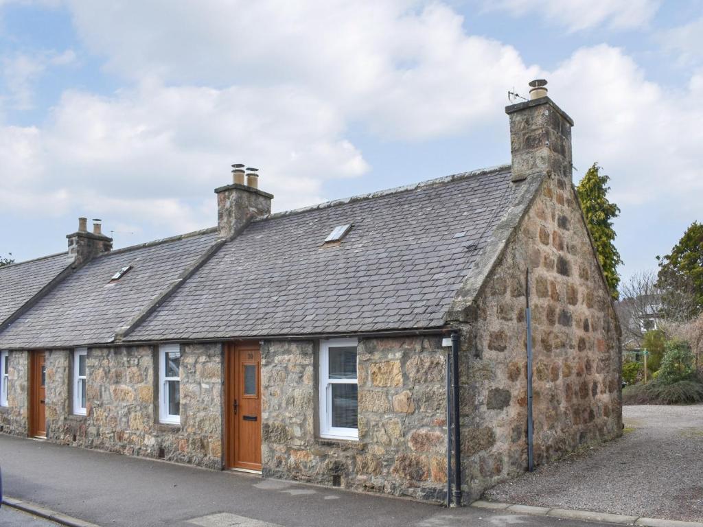 an old stone house on the side of a street at Rinnes Cottage in Aberlour