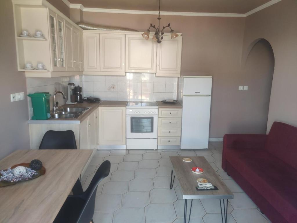 kuchnia z białymi szafkami, stołem i czerwoną kanapą w obiekcie Monemvasia Lazarus Beach Apartment w mieście Monemwasia