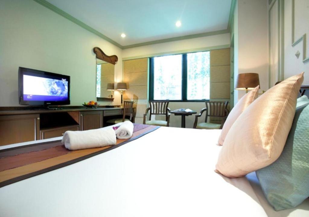 1 dormitorio con 1 cama grande y TV en Majestic Suites Hotel en Bangkok