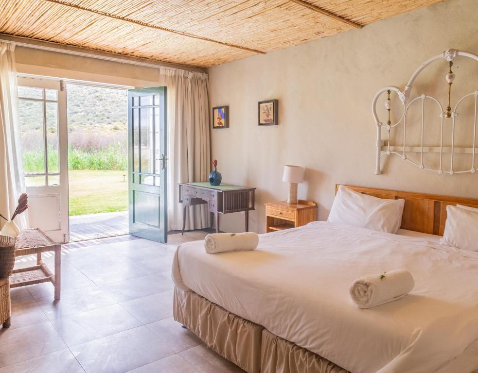 a bedroom with a bed and a table and a desk at Karoo 1 Hotel Village in De Doorns
