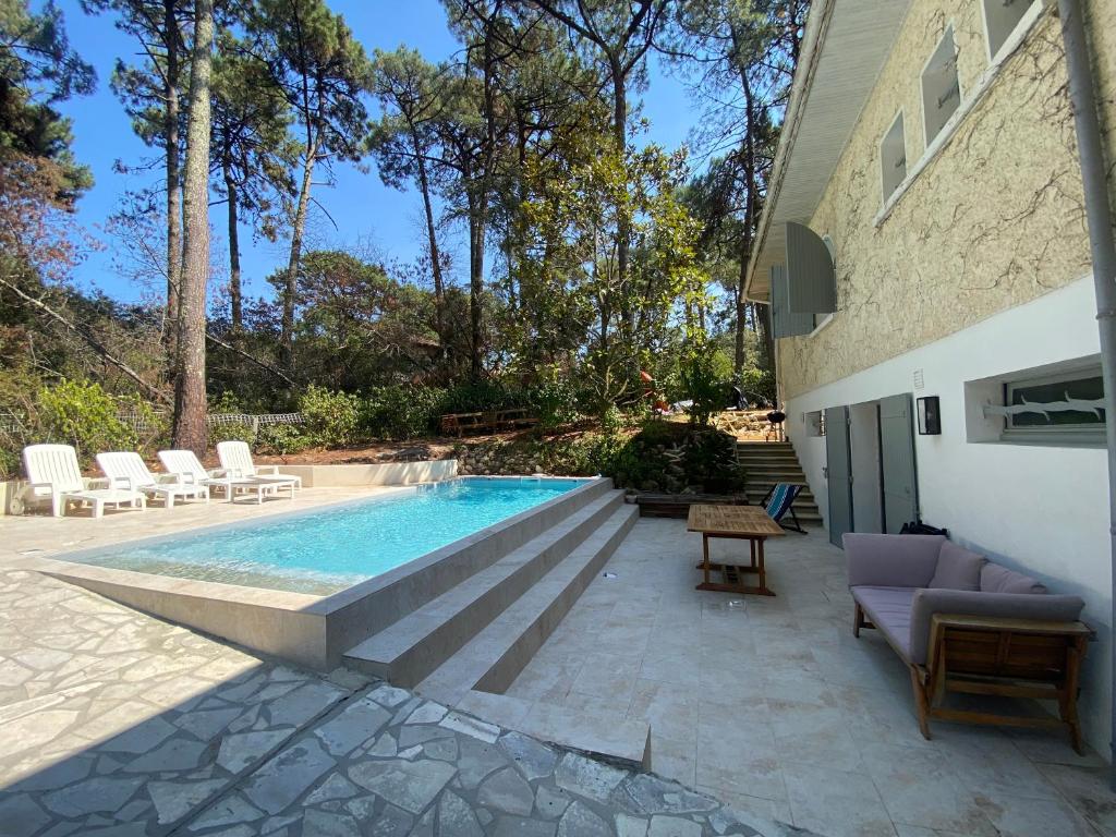 una piscina en un patio trasero con sillas y mesa en Pyla sur mer proche plages appartement avec piscine en Pyla-sur-Mer