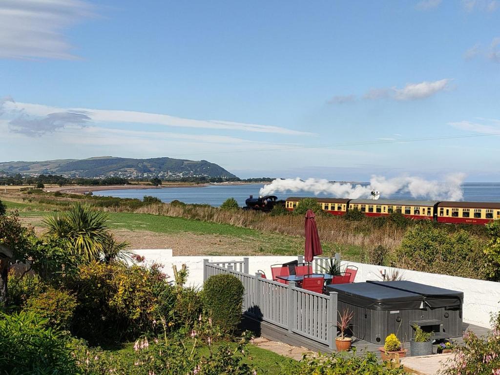 a train traveling down tracks next to a body of water at Blue Anchor House - Seaview, Hot Tub Apartments in Blue Anchor