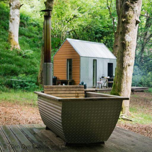 uma banheira de madeira sentada num deque de madeira com um pequeno barracão em North Lodge & River Cabin em Banchory