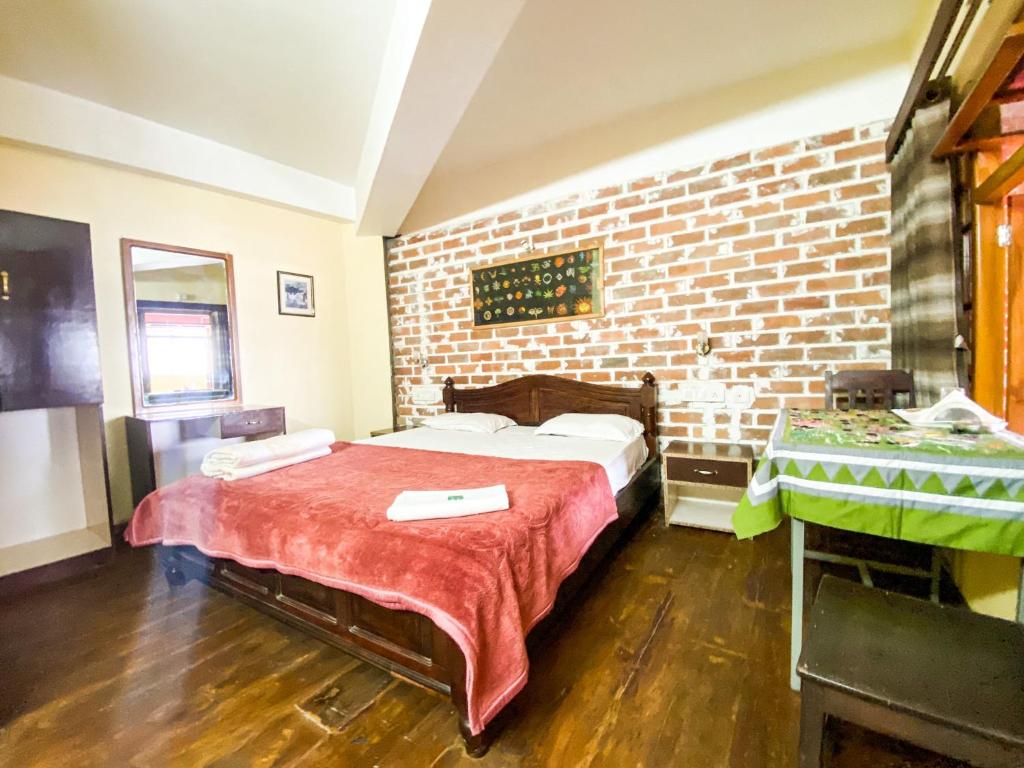 a room with a bed and a brick wall at King Thai Hotel and Restaurant in Kalimpong