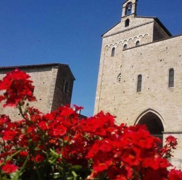 un bâtiment avec une tour aux fleurs rouges devant elle dans l'établissement La Piazzetta Affittacamere Ristorante, à Anagni