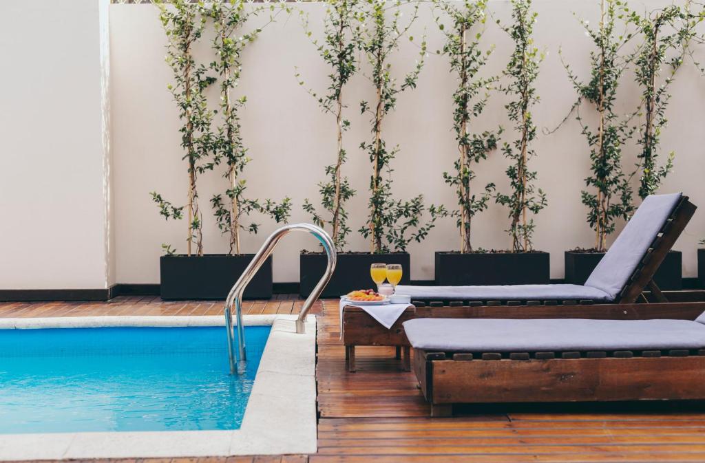 - une piscine avec 2 chaises longues et une table avec un verre de vin dans l'établissement Cyan Américas Towers Hotel, à Buenos Aires