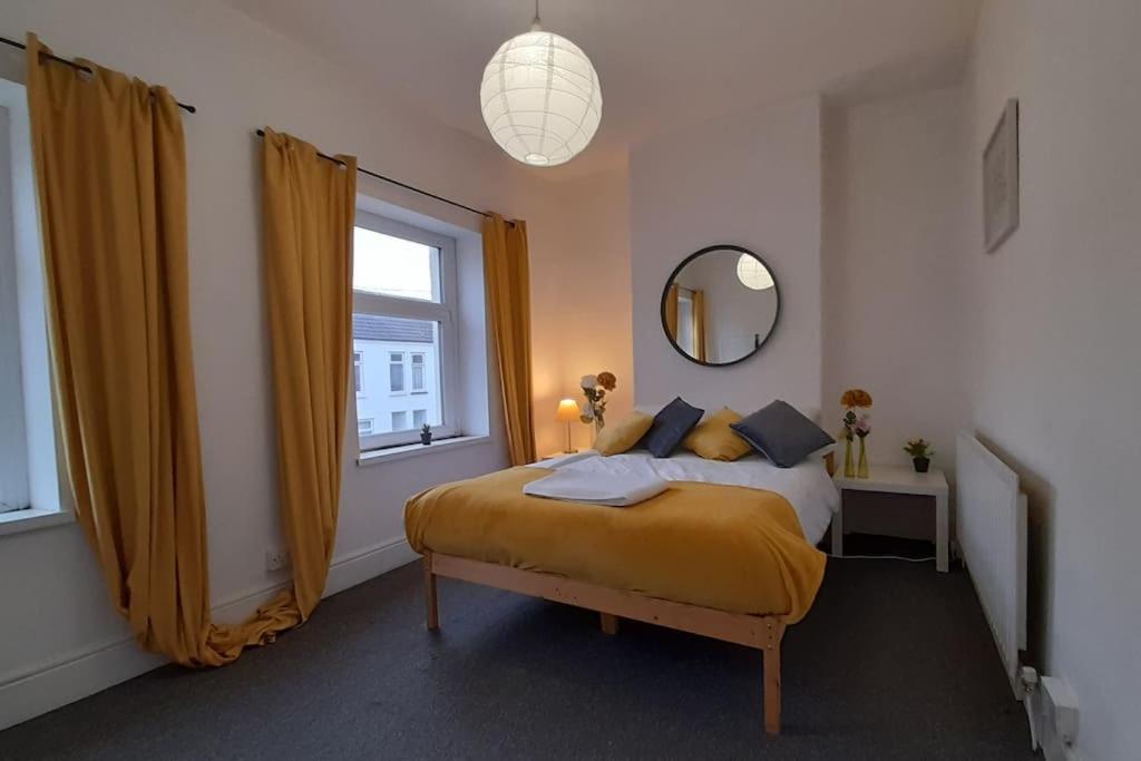 een slaapkamer met een bed met gele lakens en een raam bij Spacious 4 Bedroom, Free Netflix, Central Location in Cardiff