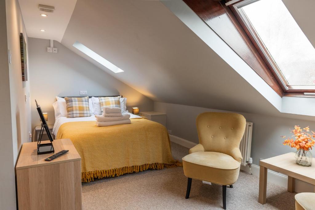 a attic bedroom with a bed and a chair at Union Street Suites in Kelso