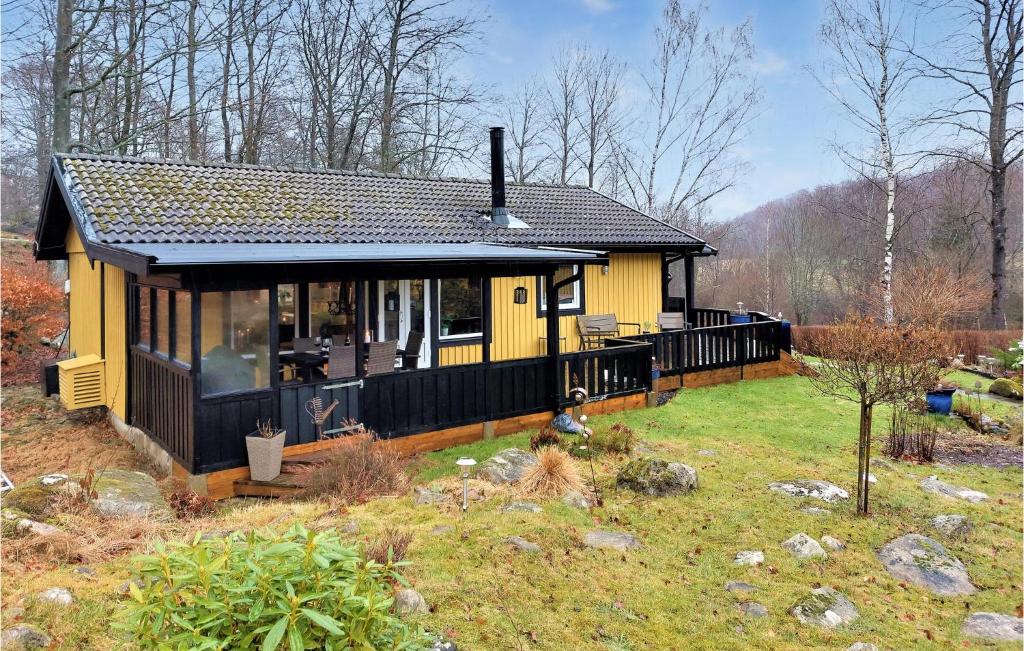 een klein geel huis met een terras in een tuin bij Stunning Home In sljunga With House A Panoramic View in Åsljunga