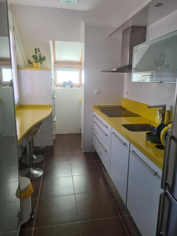 una cucina con armadi bianchi e piano di lavoro giallo di Ático Somo Beach a Somo