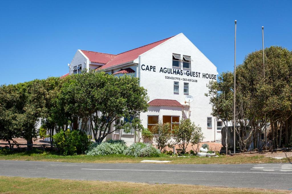 een wit gebouw met een bord aan de zijkant bij Cape Agulhas Guest House in Agulhas