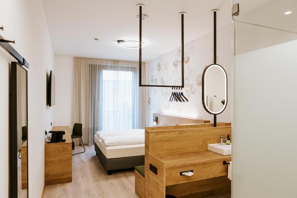 BEE GREEN Linz Self-Check-in-Hotel في لينز: غرفة نوم بسرير ومغسلة ومرآة