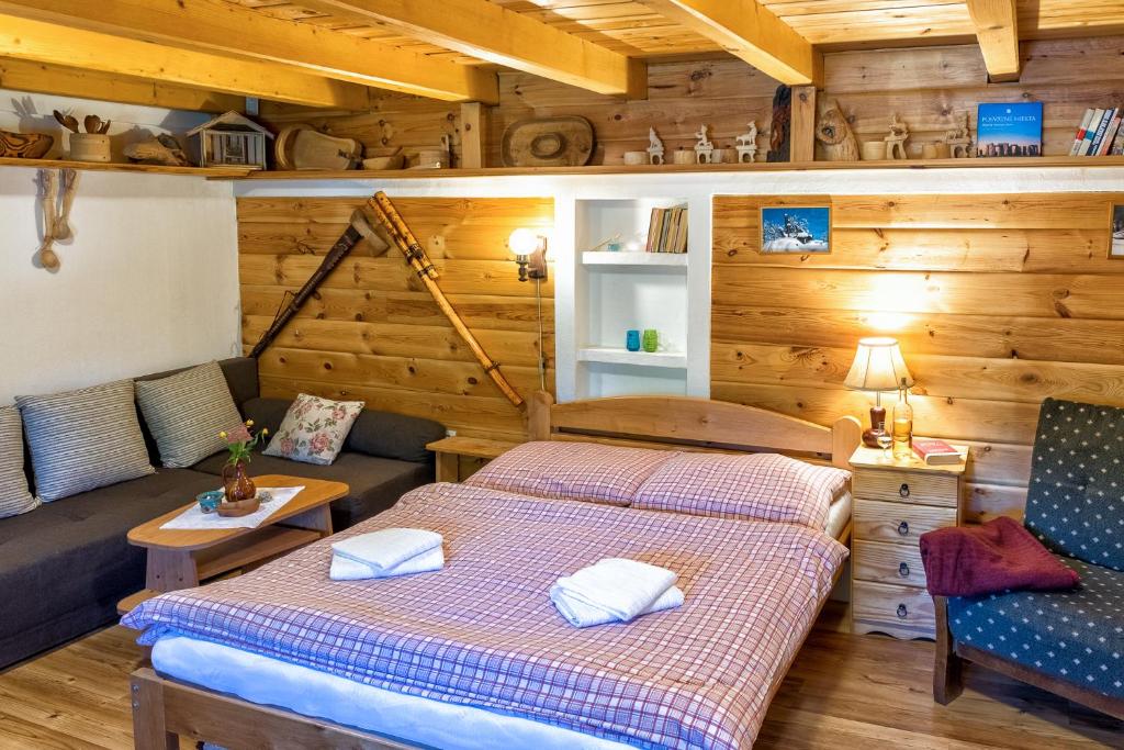 two beds and a couch in a room with wooden walls at Chalupa u Žofky in Oščadnica