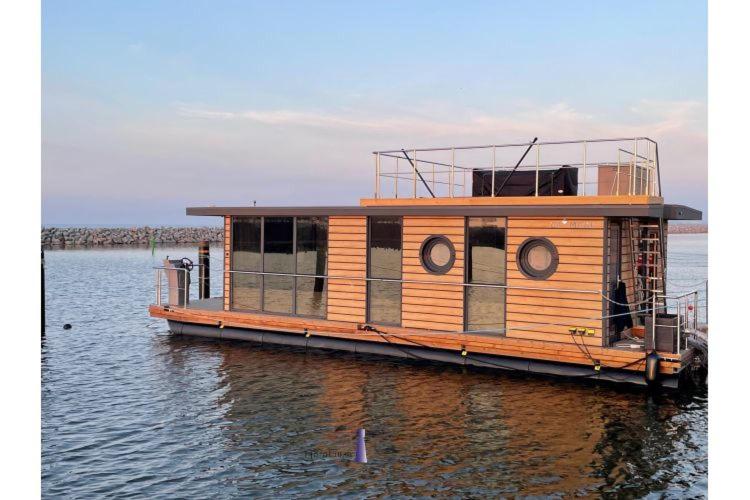 巴特Hausboot Fjord HAVEN mit Biosauna in Barth的一艘大型木船坐在水中