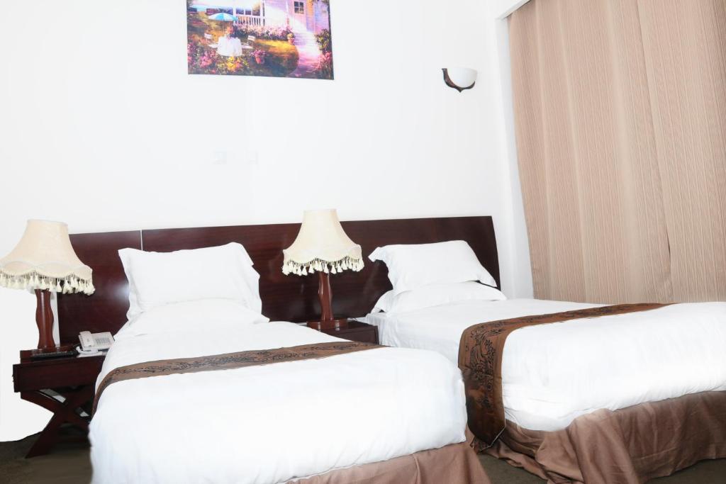 two beds in a hotel room with white sheets at AG Palace Hotel in Addis Ababa