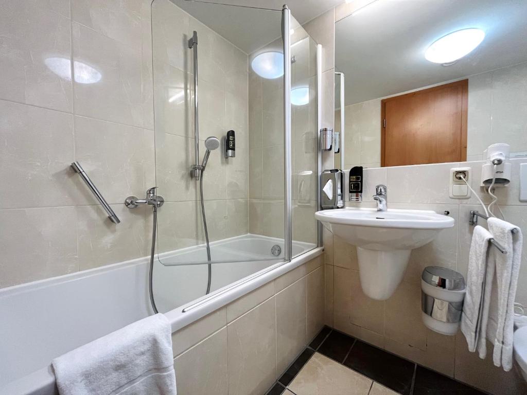 a bathroom with a shower and a sink and a bath tub at Modernes Apartment mit Blick zur Frauenkirche in Dresden