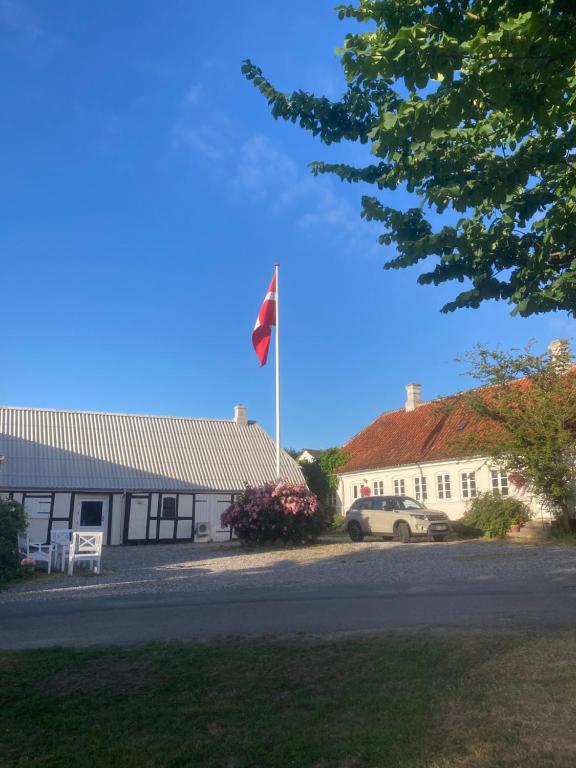 eine Flagge auf einer Stange vor einem Gebäude in der Unterkunft Vejskrækgården in Fæbæk