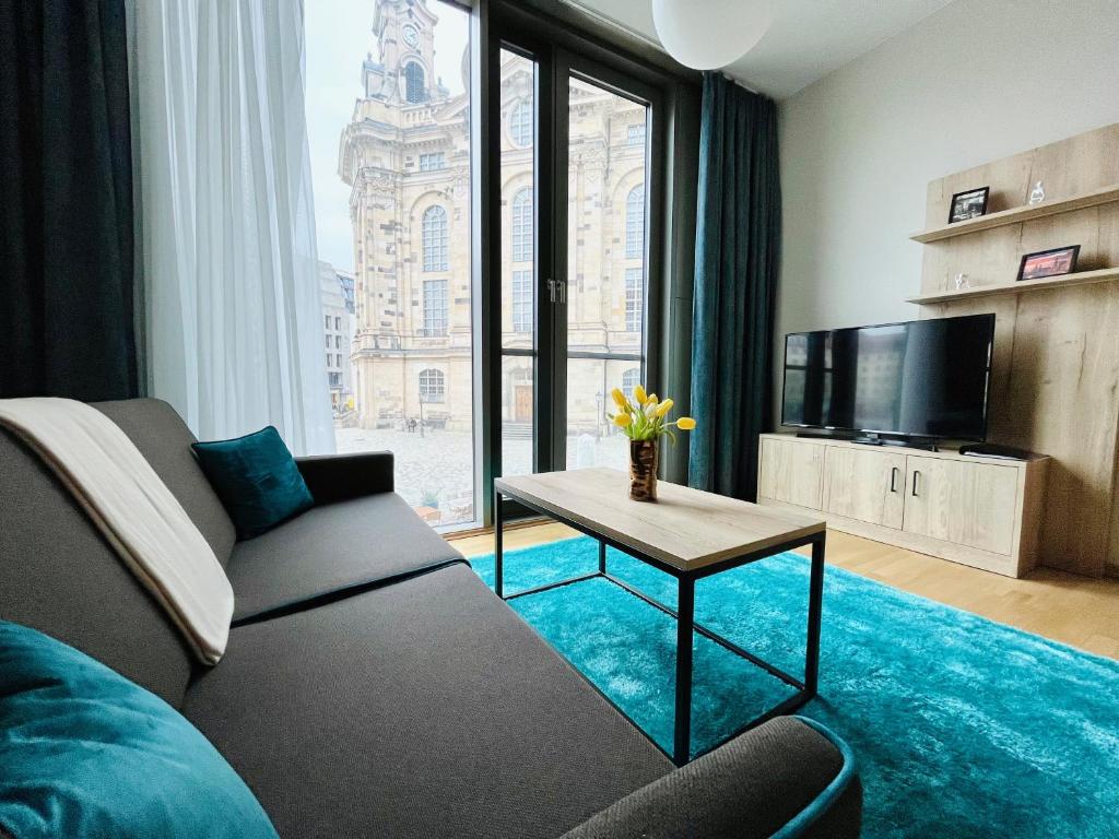 a living room with a couch and a tv and a table at Panoramastudio mit Blick zur Frauenkirche in Dresden