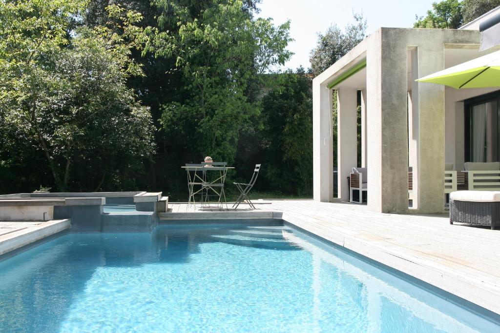 a swimming pool in front of a house with a table at Villa d'architecte Uzes in Sainte Anastasie - Aubarne