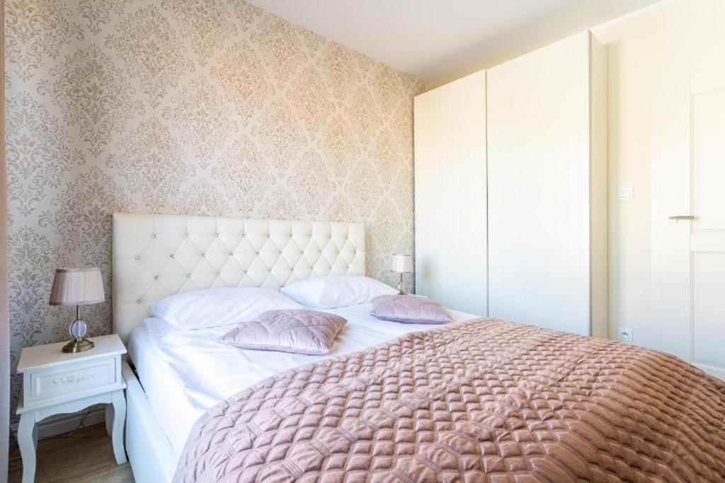 a bedroom with a large bed with pink sheets and pillows at Royal Apartment Old Town Gdańsk Tartaczna 46 in Gdańsk