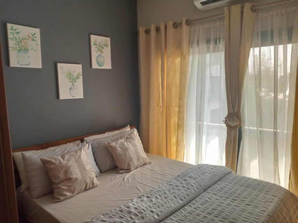 1 dormitorio con 1 cama y una ventana con cortinas en Aquaview en Bijilo
