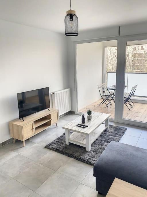 uma sala de estar com uma televisão de ecrã plano e uma mesa em CAPRI - Sublime T2 Patte d'oie (Netflix, Terrasse) em Toulouse