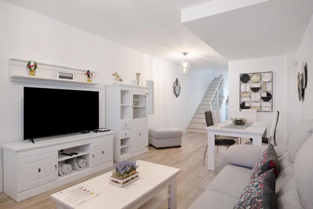 uma sala de estar branca com uma televisão e um sofá em Casa Reguemar em Arrecife