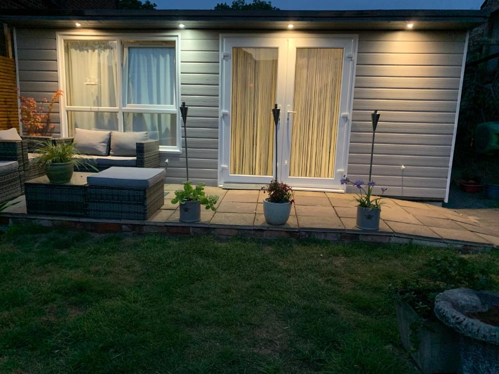 a patio with a couch and potted plants in front of a house at Pet friendly, disabled friendly cabin close to the humber and immingham in Goxhill