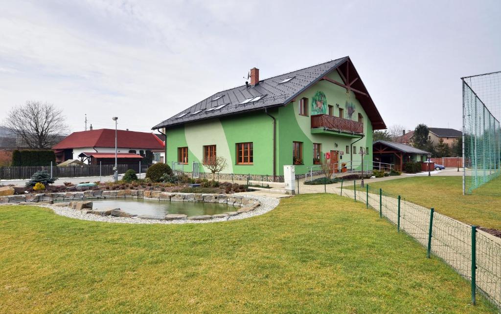 una casa verde con un estanque frente a un campo en Restaurace a penzion Kamenec, en Jilešovice