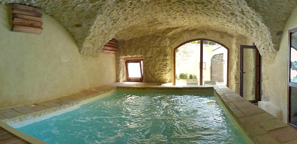 una piscina cubierta en una casa con una pared de piedra en Clos de Raveyron, en Vallon-Pont-dʼArc