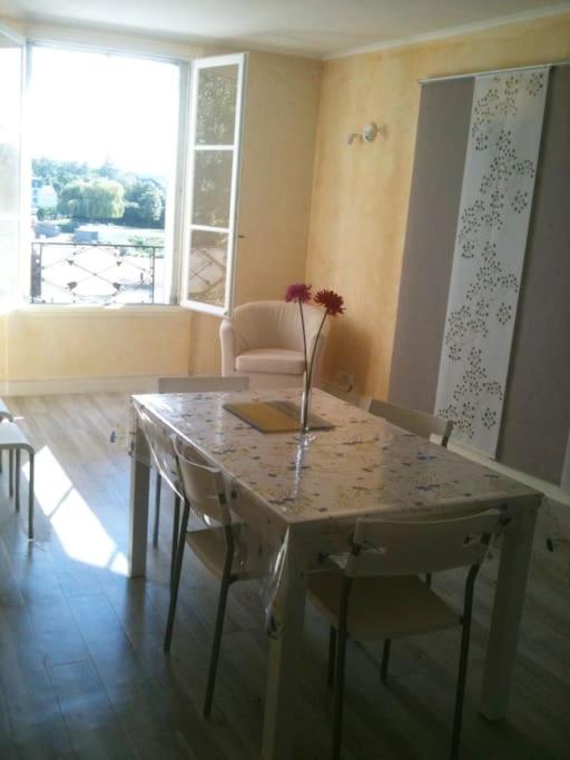 a dining room table with a vase of flowers on it at Vaste appartement avec vue sur la Vienne in Chinon