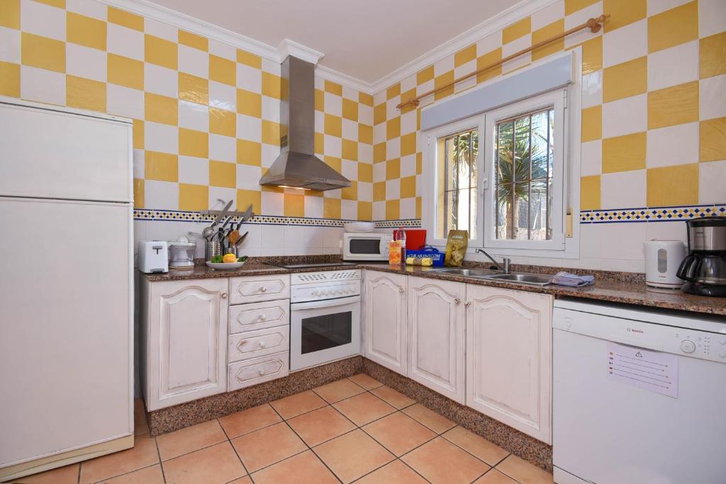 una cocina con electrodomésticos blancos y azulejos amarillos y blancos en Monte Malva, en Jávea