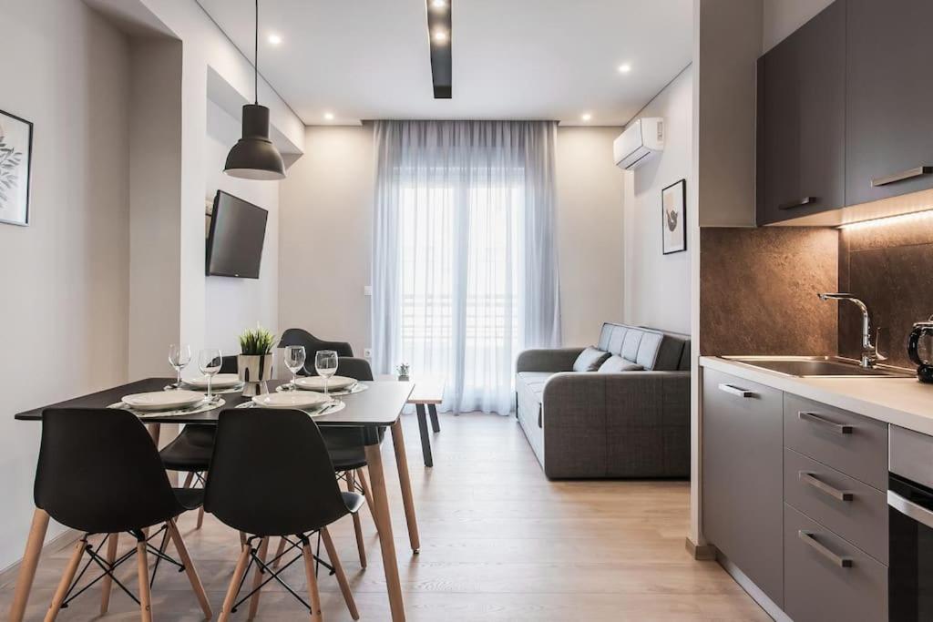 a kitchen and a living room with a table and chairs at Piraeus Deluxe 2BDR Apt - near metro and port in Piraeus