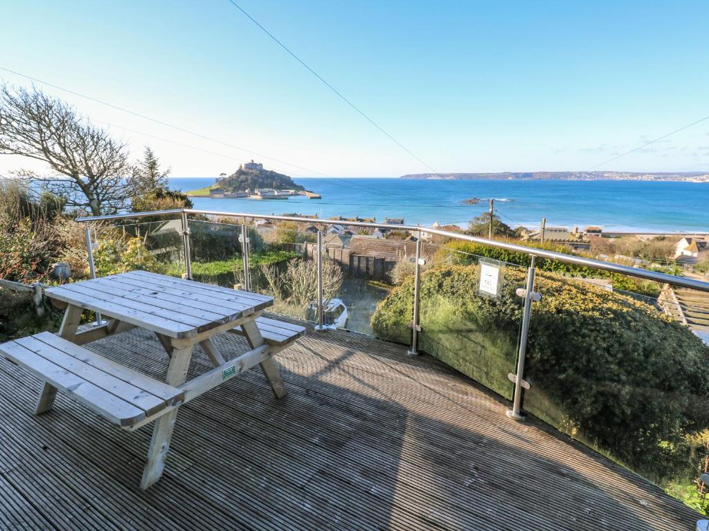 a picnic table on a deck with a view of the ocean at Rosemount in Marazion