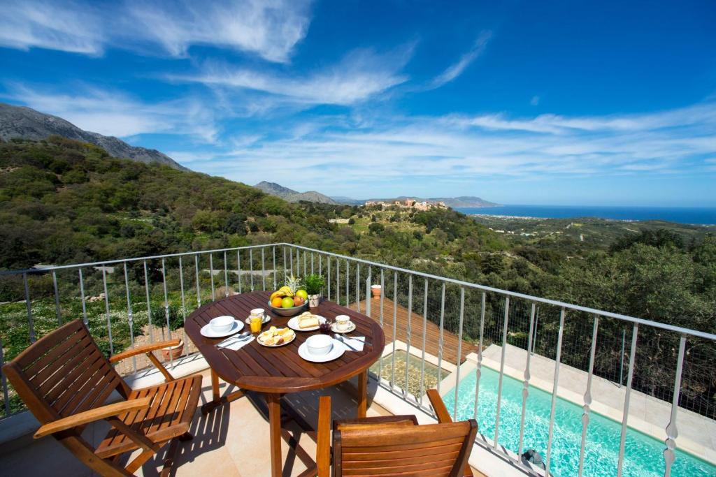 Villa Cretan View with Heated Swimming Pool في Pátima: طاولة على شرفة مطلة على المحيط