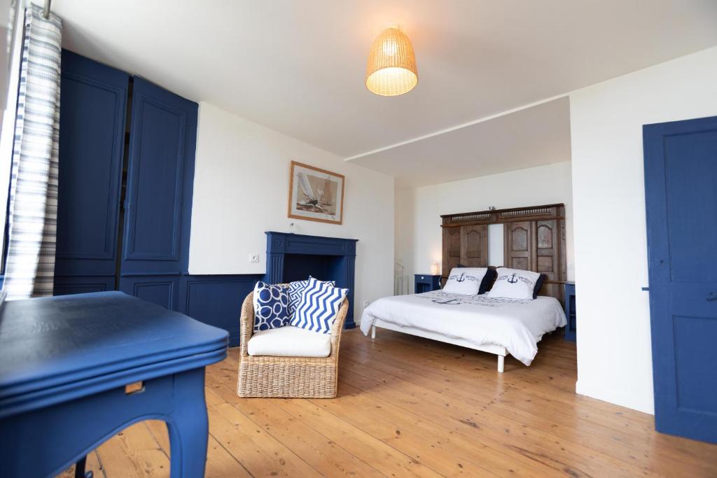 1 dormitorio con armarios azules, 1 cama y 1 silla en La Grève du Portrieux, en Saint-Quay-Portrieux